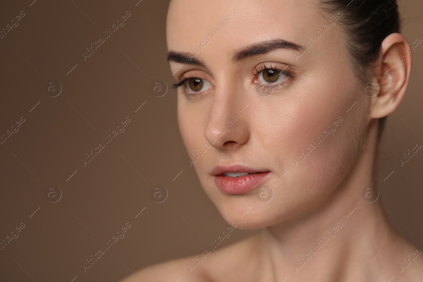 Photo of Beautiful young woman with healthy skin on brown background, closeup. Space for text