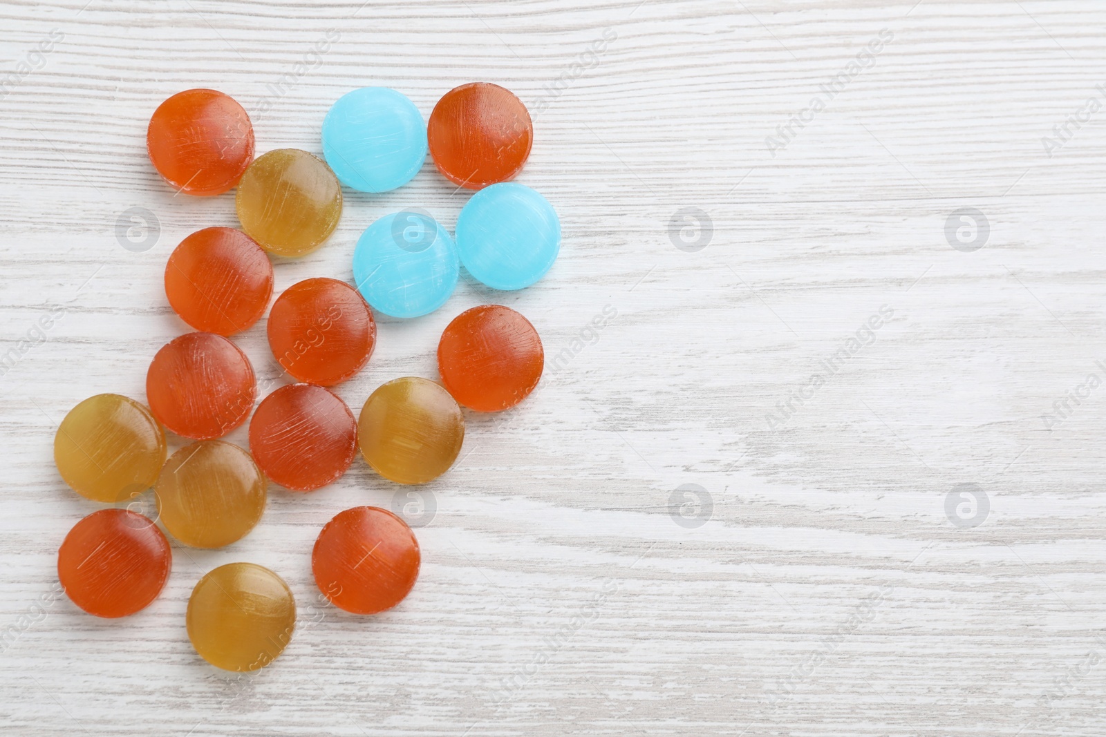 Photo of Many colorful cough drops on white wooden background, flat lay. Space for text