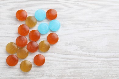 Photo of Many colorful cough drops on white wooden background, flat lay. Space for text
