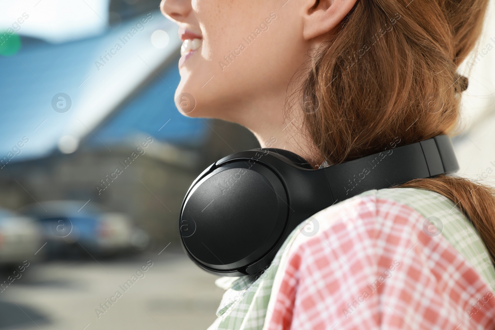 Photo of Smiling woman with headphones outdoors, closeup. Space for text