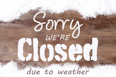 Image of Sorry we are closed due to weather sign. Text and snow on wooden background