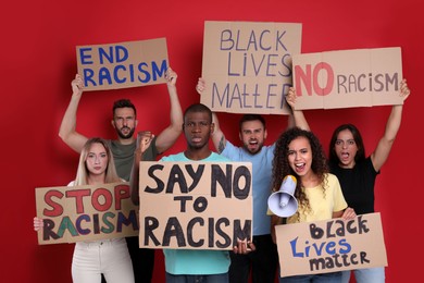 Photo of Protesters demonstrating different anti racism slogans on red background. People holding signs with phrases