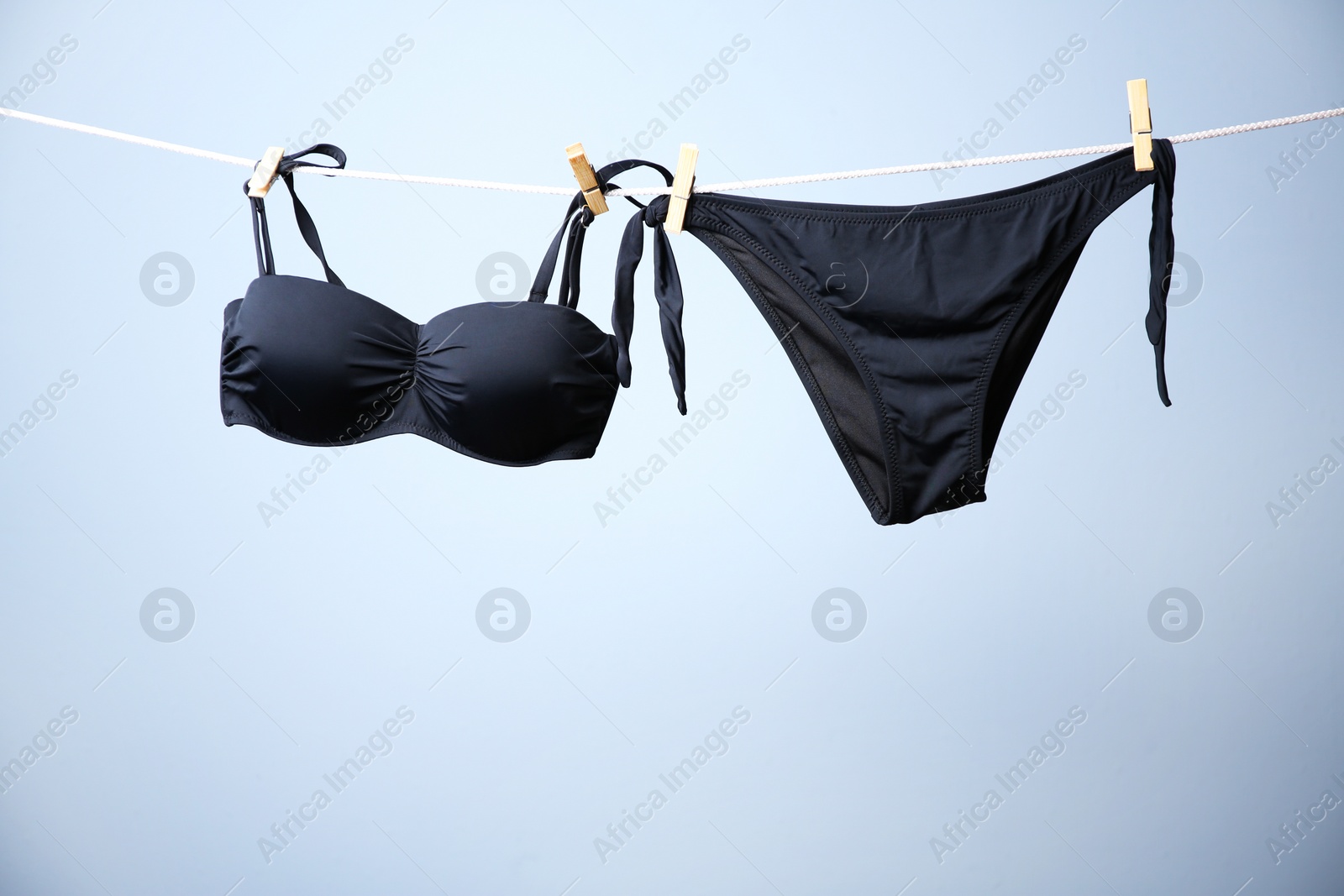 Photo of Stylish bikini hanging on rope against color background