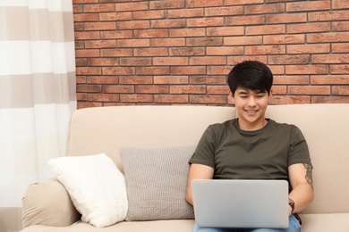 Photo of Man in casual clothes with laptop in living room