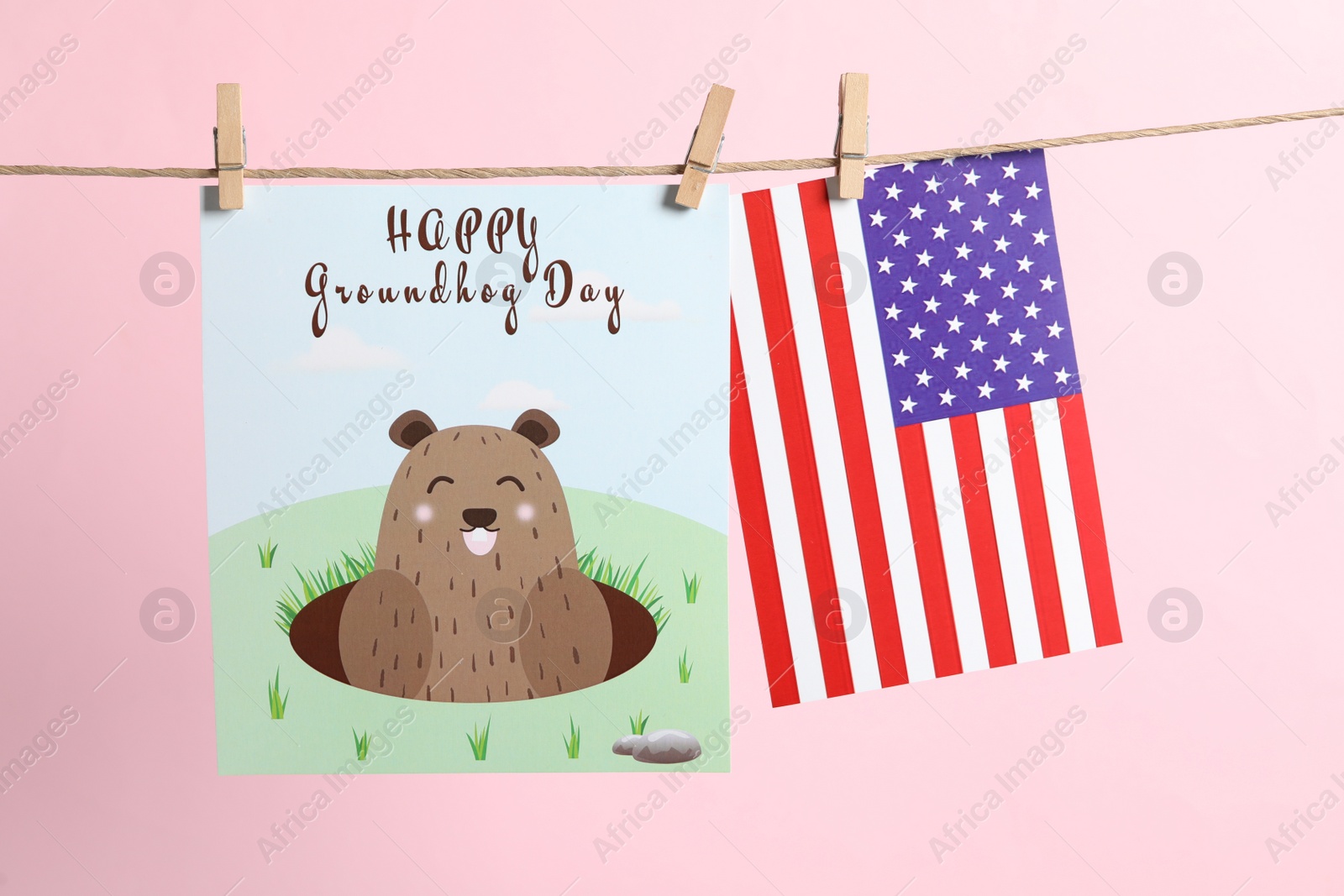 Photo of Happy Groundhog Day greeting card and American flag hanging on pink background