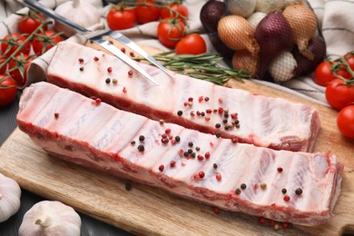 Raw pork ribs with peppercorns on table, closeup
