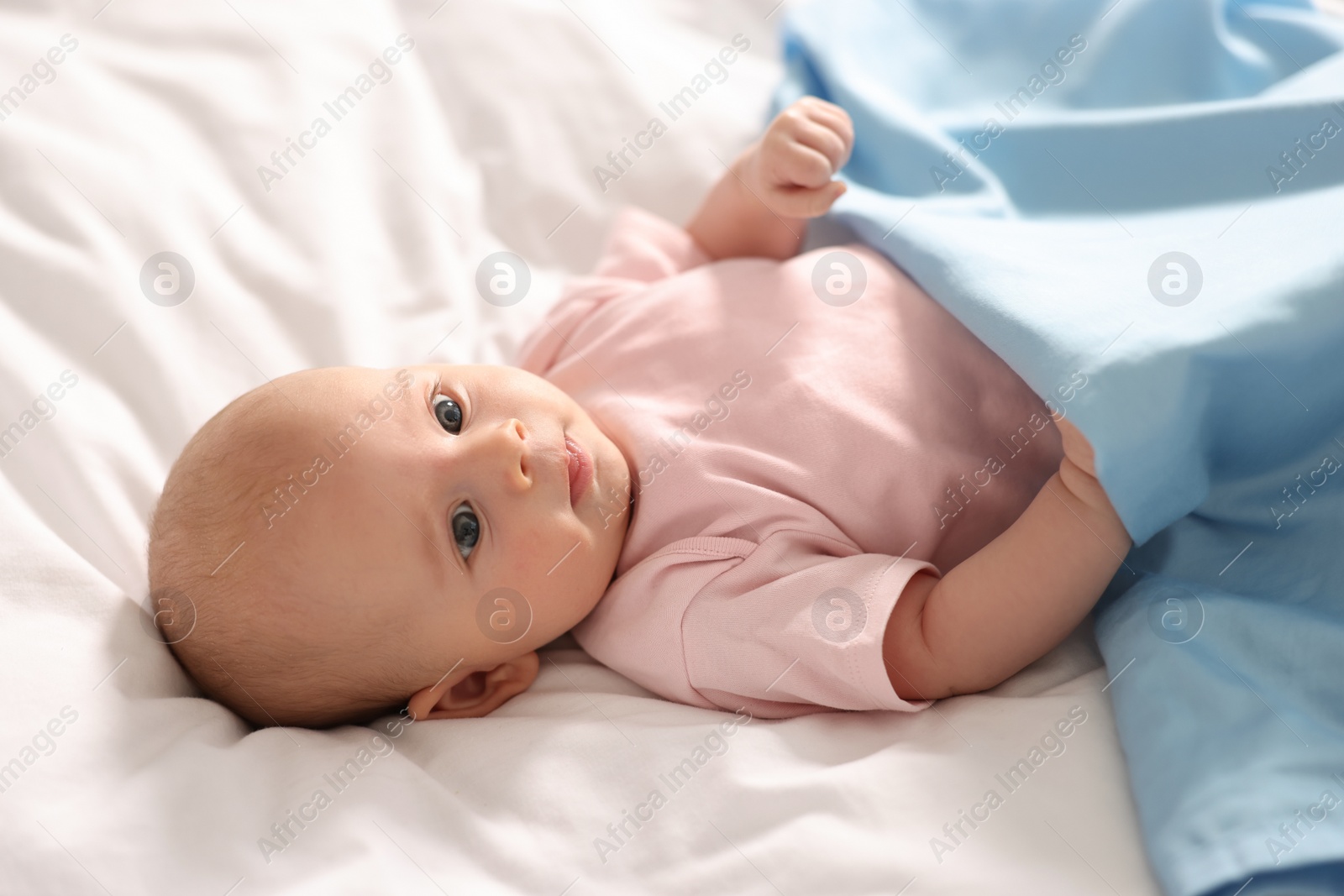 Photo of Cute little baby lying on white sheets