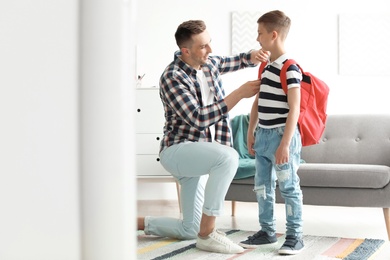 Young man helping his little child get ready for school at home