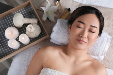 Photo of Beautiful Asian woman lying on massage table in salon, top view