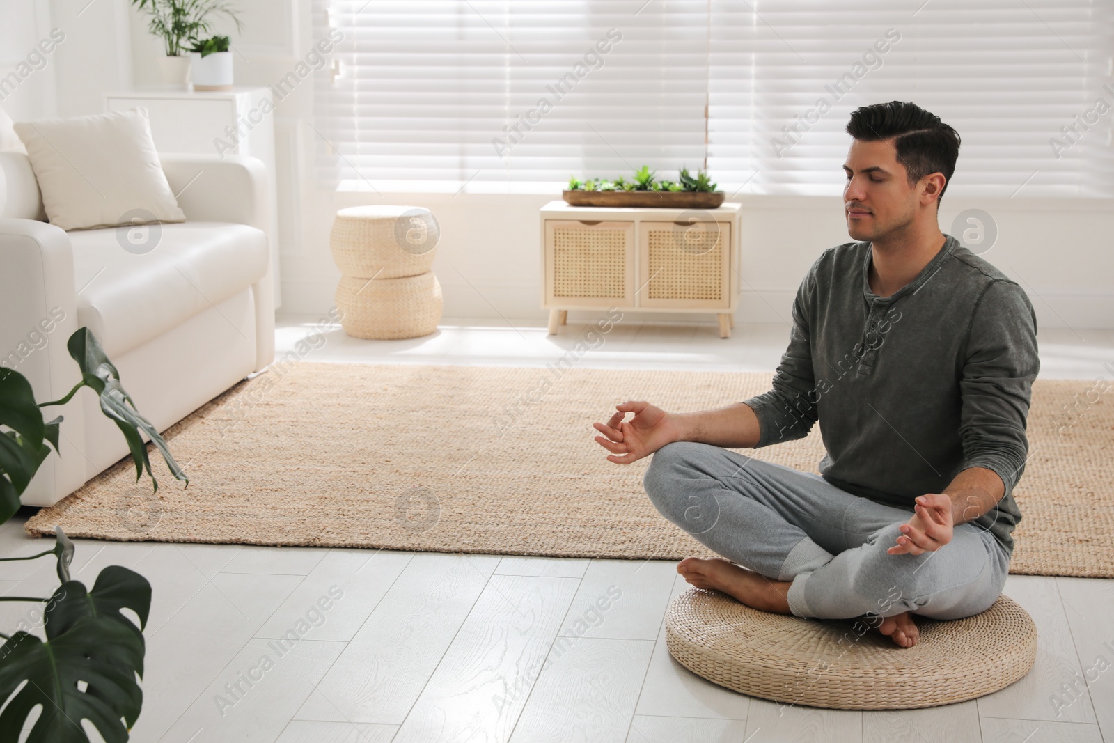 Photo of Man meditating on wicker mat at home. Space for text