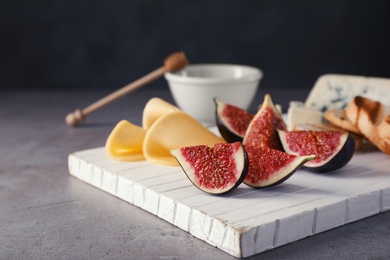 Photo of Wooden board with ripe fig slices on grey table