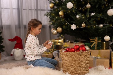 Photo of Cute little child decorating Christmas tree at home