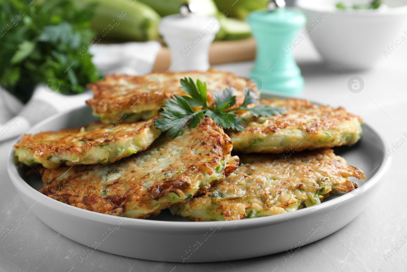 Photo of Delicious zucchini fritters served on light table, closeup