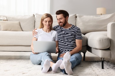 Photo of Happy couple with laptop on floor at home