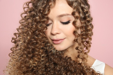 Portrait of beautiful young woman with shiny wavy hair on color background, closeup