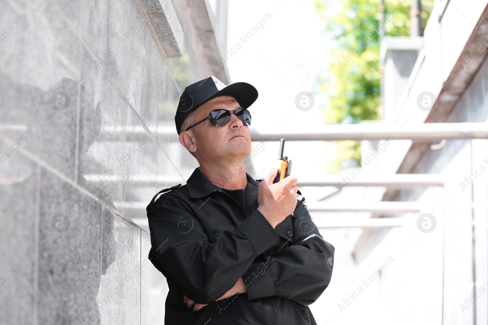 Photo of Male security guard using portable radio transmitter outdoors