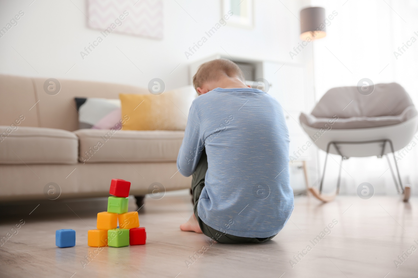Photo of Lonely little boy with cubes sitting on floor at home. Autism concept