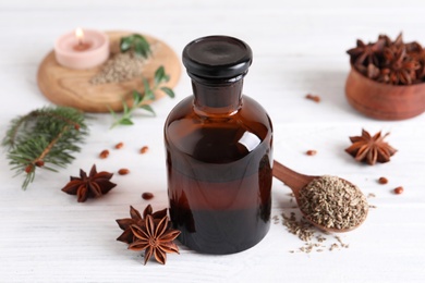 Photo of Anise essential oil and spice on white wooden table