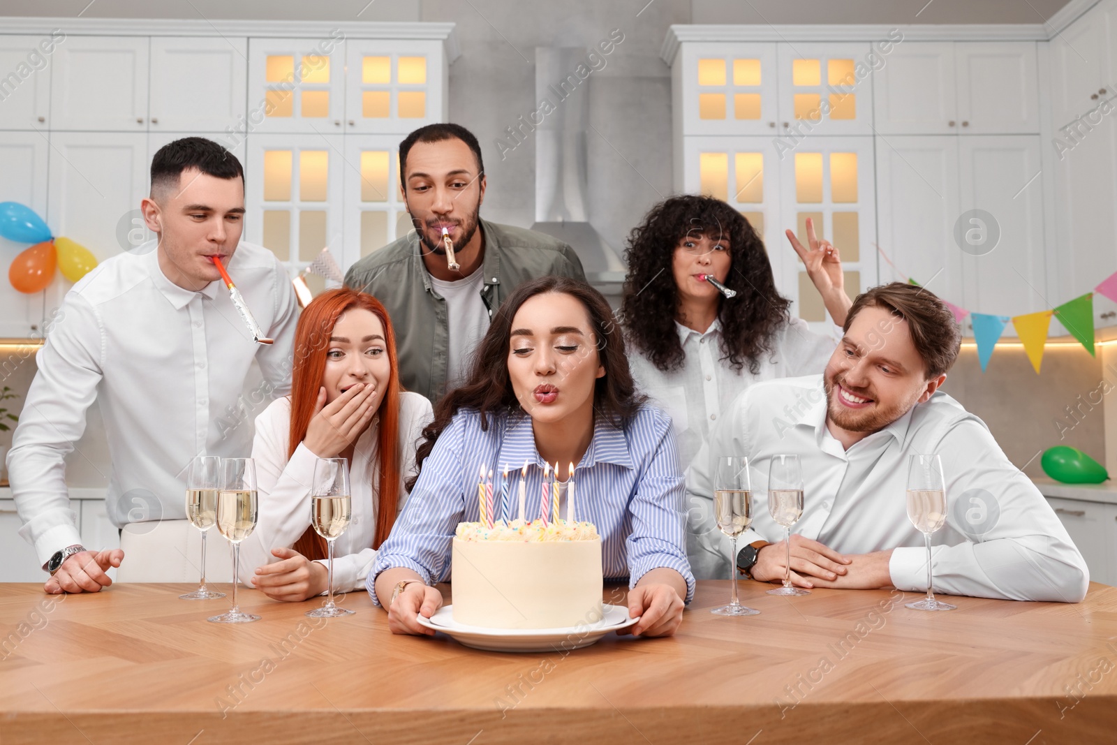 Photo of Happy friends with tasty cake celebrating birthday in kitchen