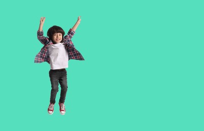 Image of Happy boy jumping on turquoise background, space for text