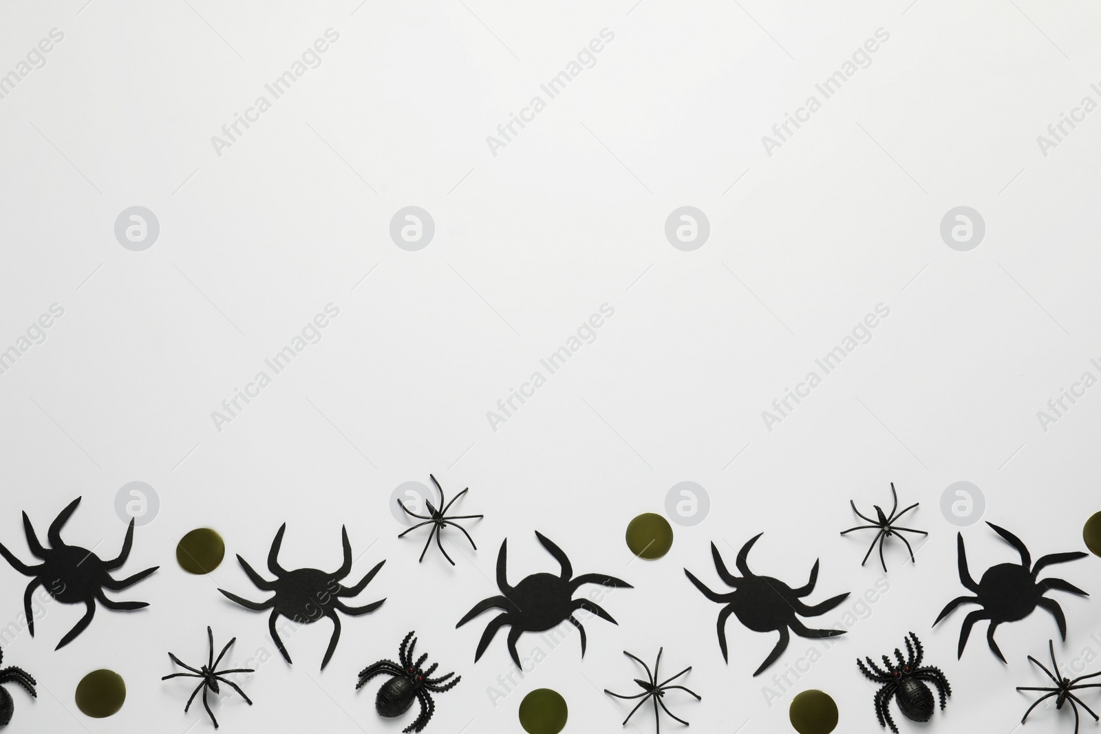 Photo of Flat lay composition with spiders and golden confetti on white background, space for text. Halloween celebration