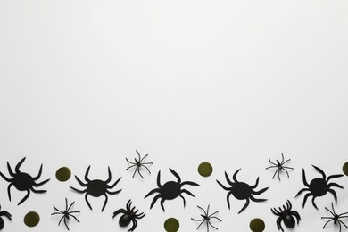 Flat lay composition with spiders and golden confetti on white background, space for text. Halloween celebration