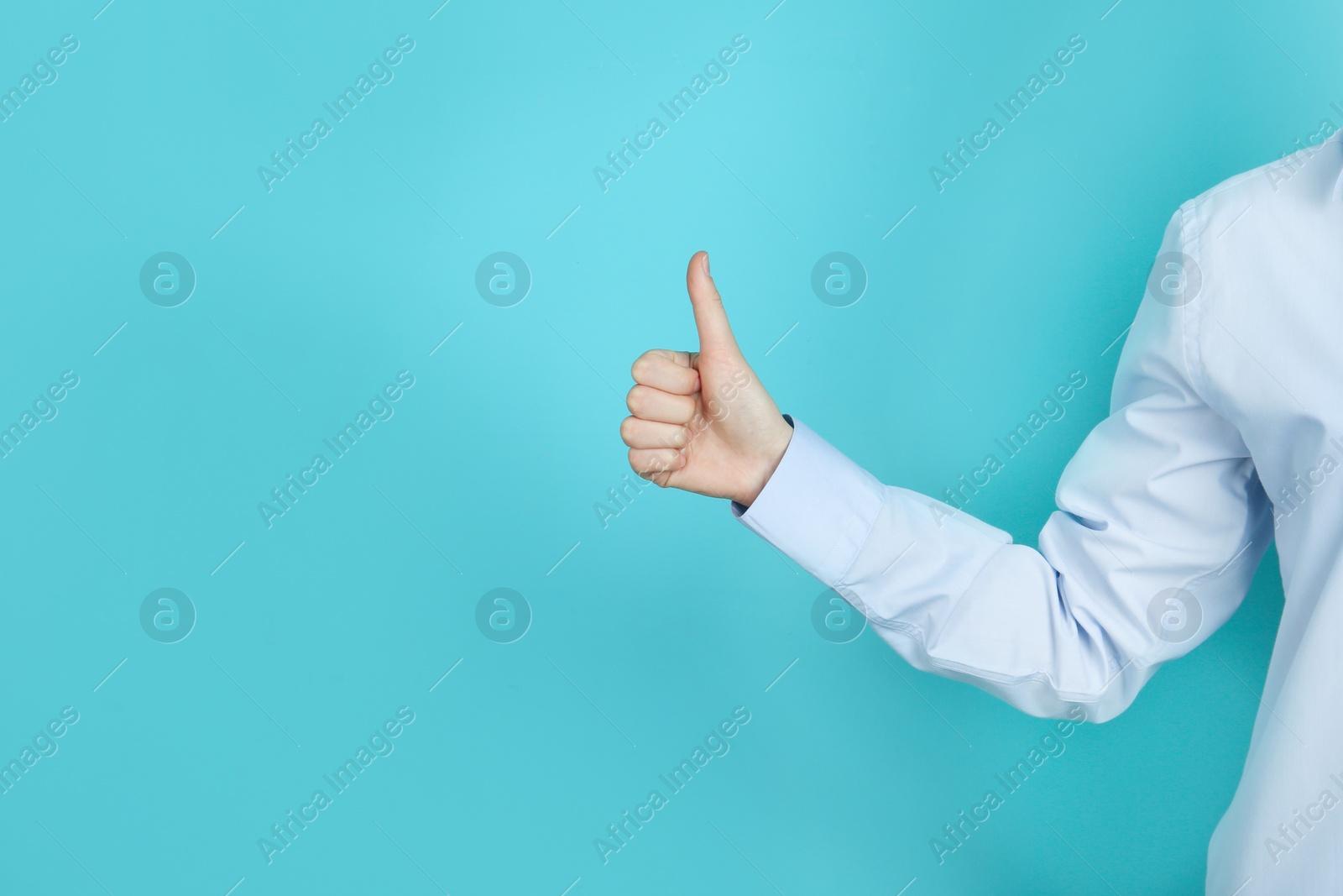 Photo of Young woman showing thumb sign on color background. Space for text