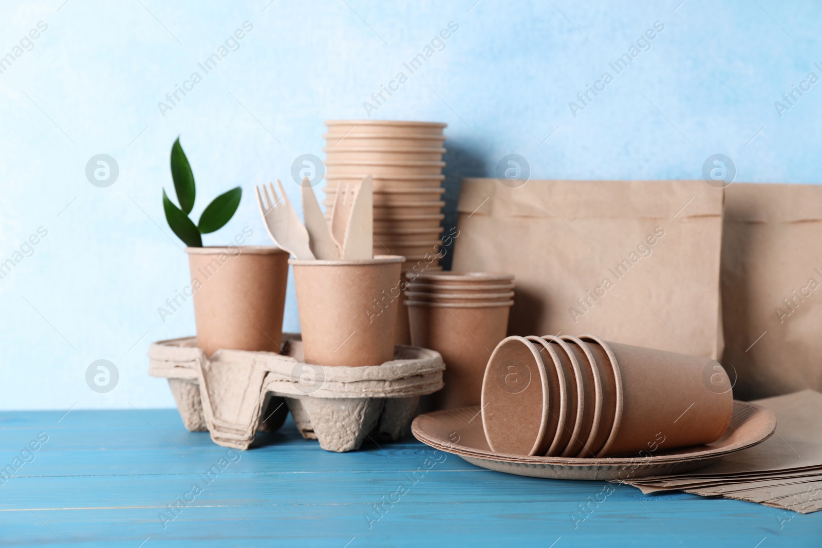 Photo of Set of disposable eco friendly dishware on light blue wooden table