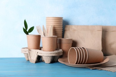 Set of disposable eco friendly dishware on light blue wooden table