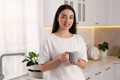Photo of Happy woman with cup of drink in kitchen. Lazy morning