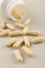 Photo of Bottle and vitamin capsules on light background, closeup