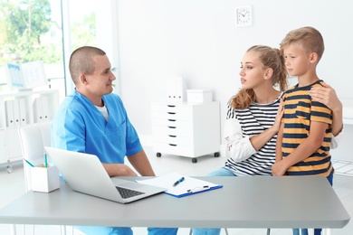 Male medical assistant consulting mother with son in clinic