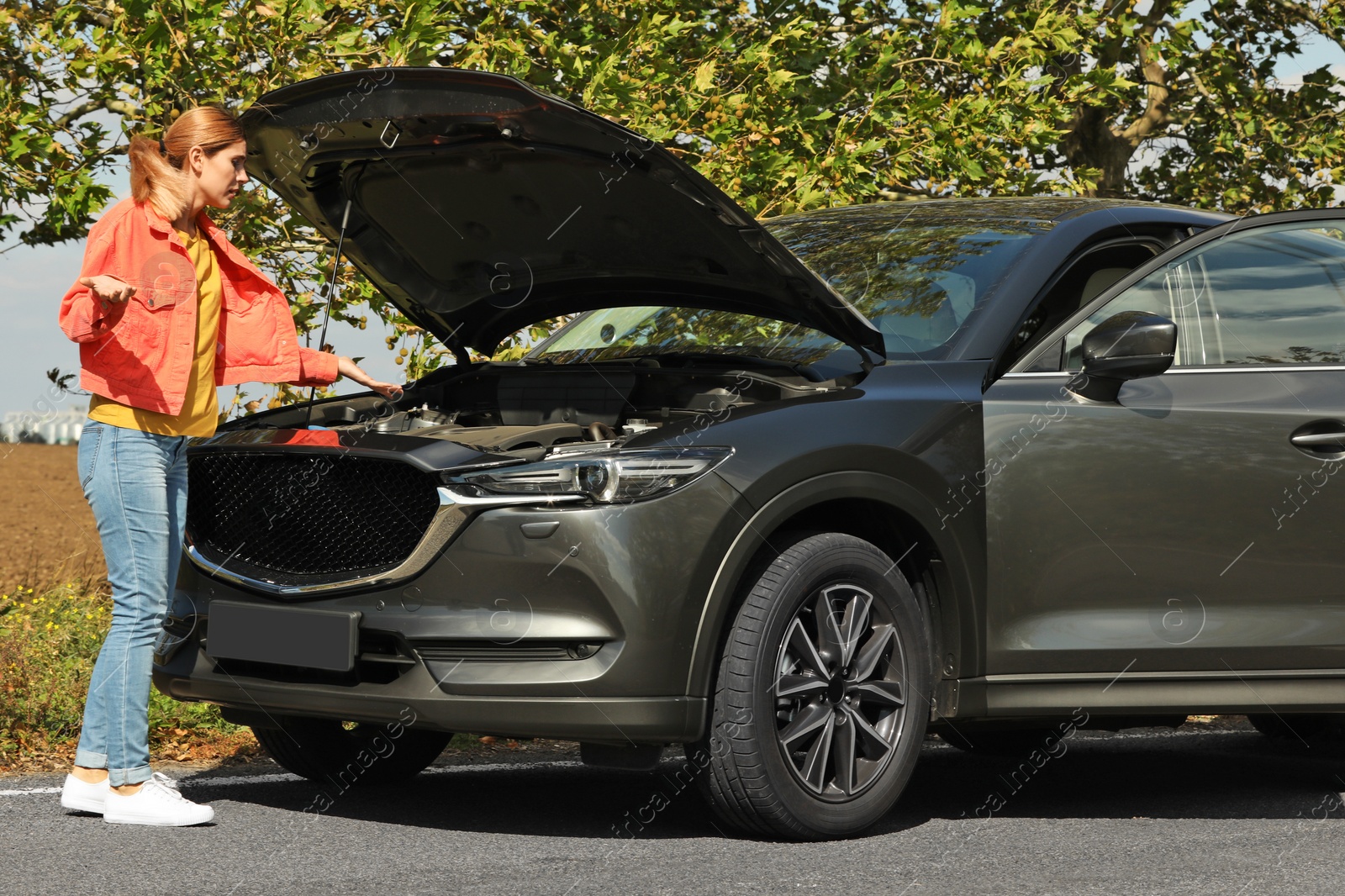 Photo of Woman near broken car on road. Auto insurance