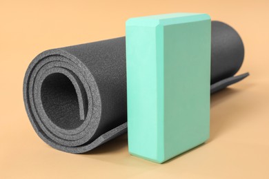Photo of Grey exercise mat and yoga block on beige background