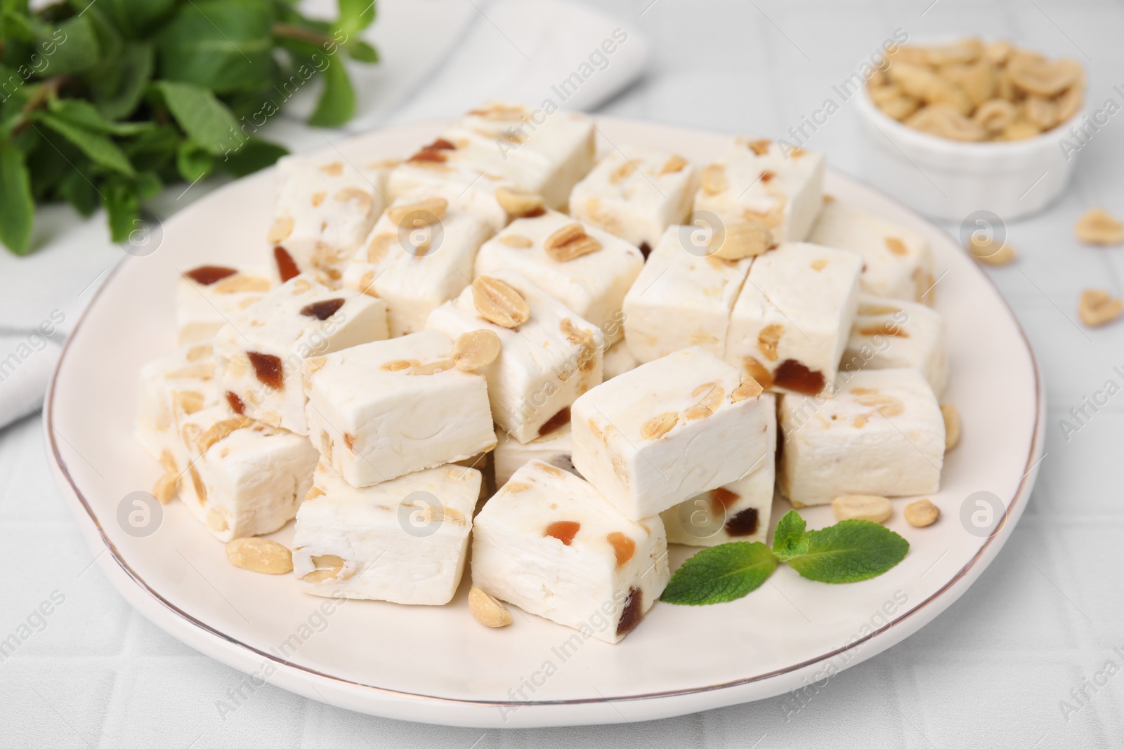 Photo of Pieces of delicious nutty nougat on plate, closeup