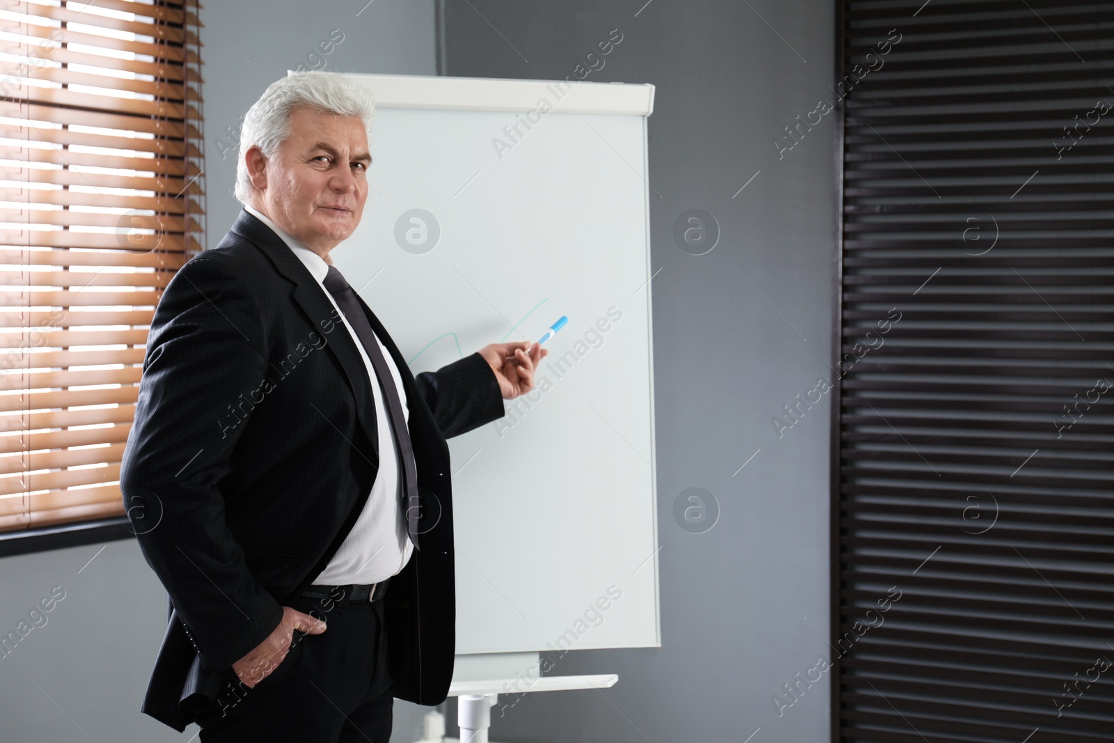 Photo of Senior business trainer near flip chart in office