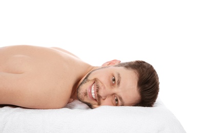 Handsome man relaxing on massage table against white background. Spa service