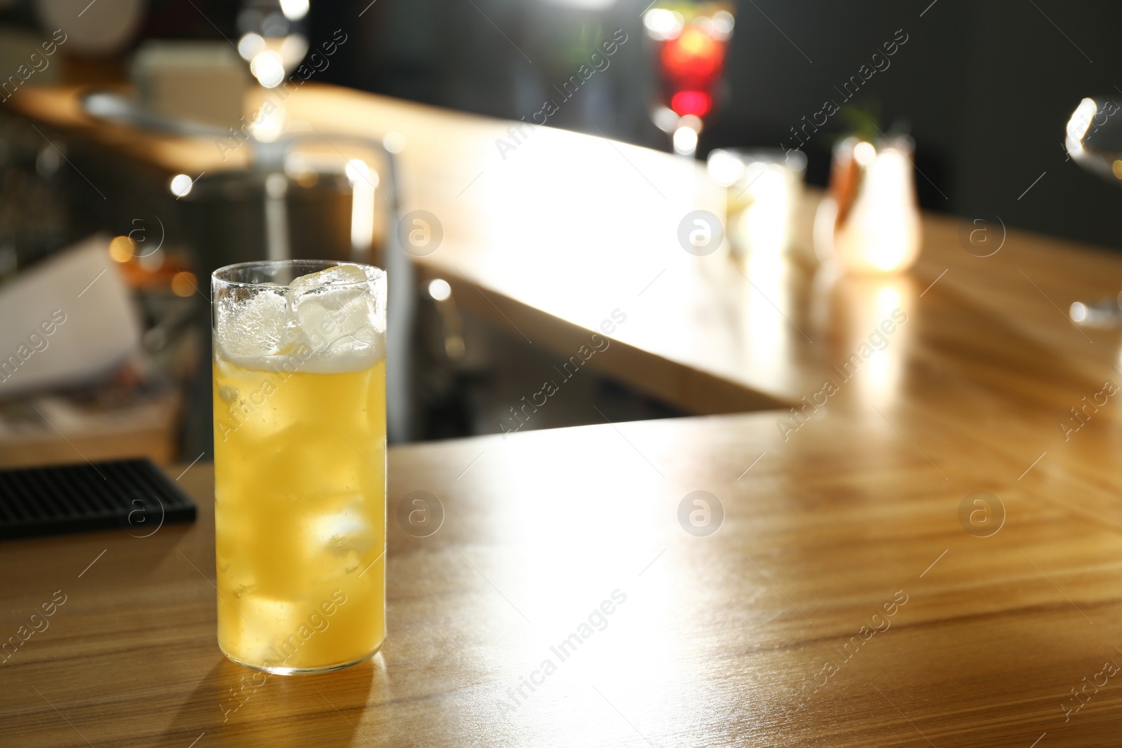 Photo of Glass of delicious cocktail with vodka on wooden counter in bar. Space for text