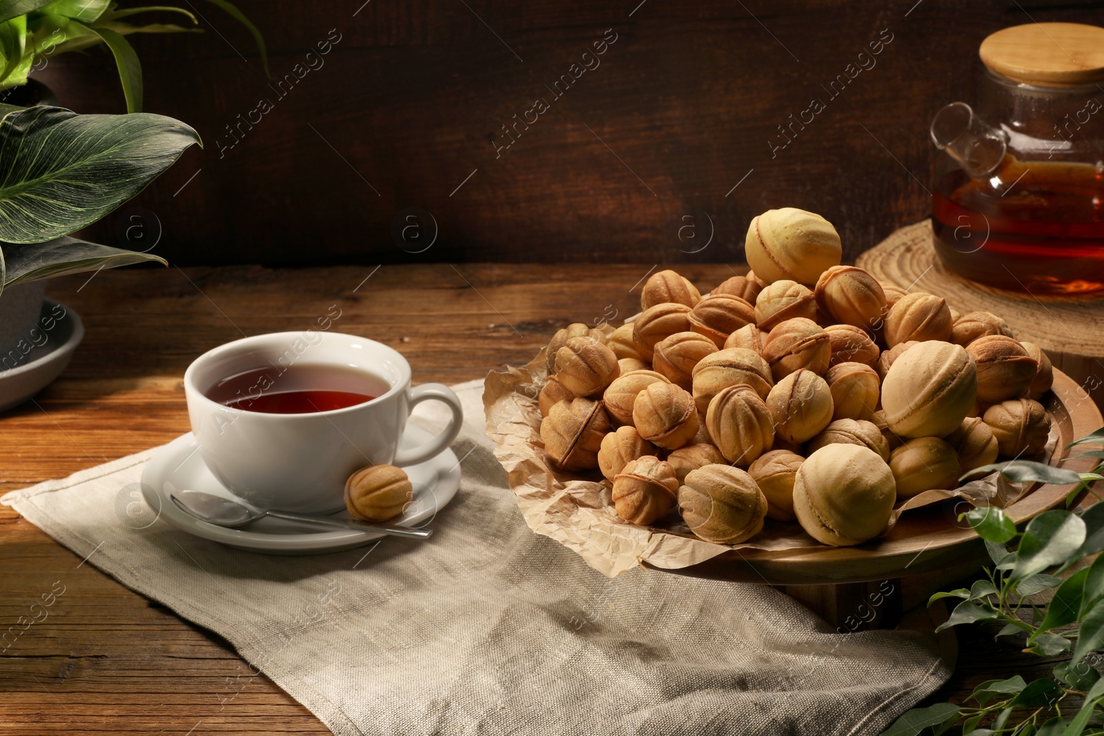 Photo of Aromatic walnut shaped cookies and tea on wooden table. Homemade pastry carrying nostalgic atmosphere