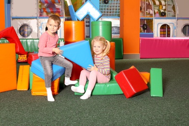 Cute children playing with colorful building blocks indoors