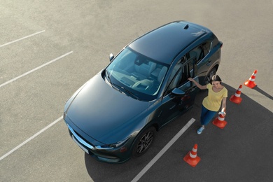 Photo of Young woman near car and traffic cones outdoors, above view. Driving school exam