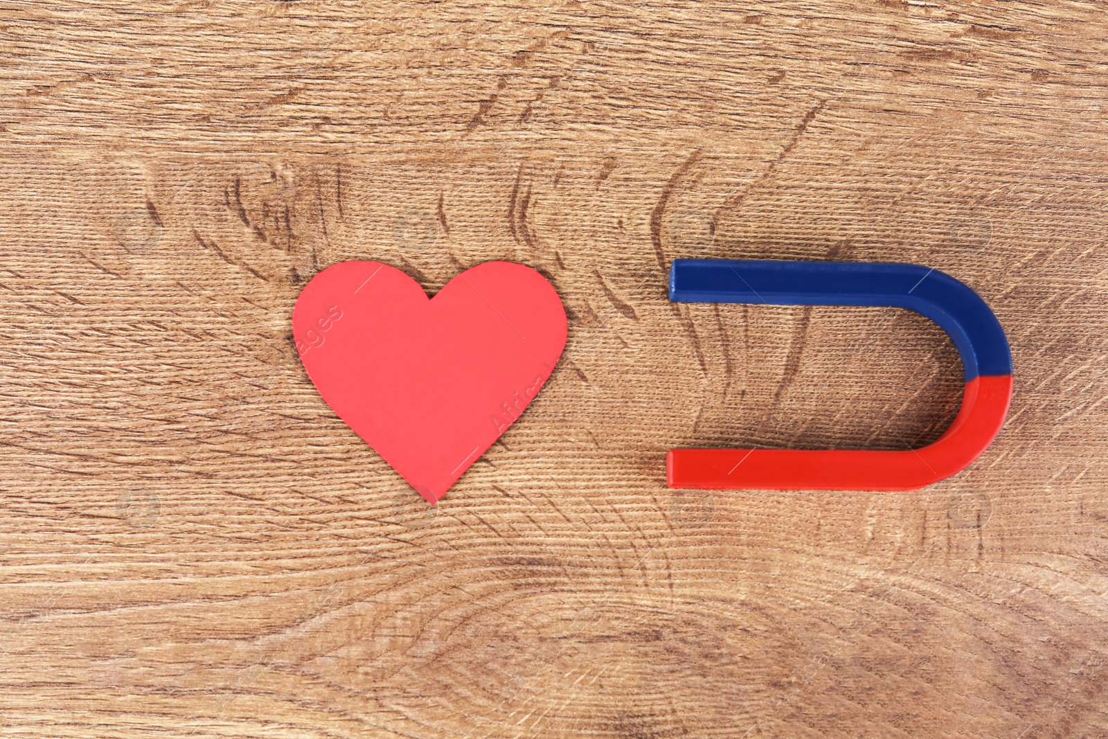 Photo of Magnet and red heart on wooden table, flat lay