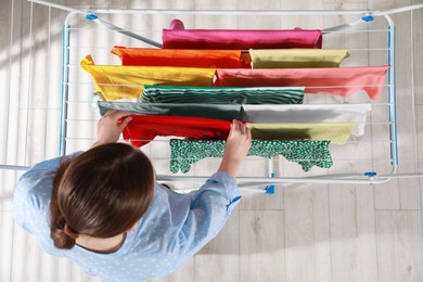 Photo of Woman hanging different apparel on clothes airer, top view