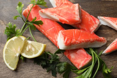 Crab sticks, lemon slices and parsley on wooden board, closeup