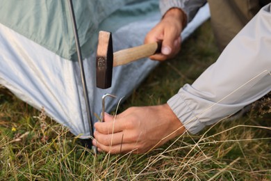 Photo of Man setting up camping tent outdoors, closeup