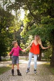 Photo of Mother and son roller skating in summer park