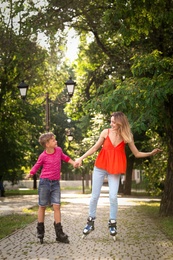 Mother and son roller skating in summer park