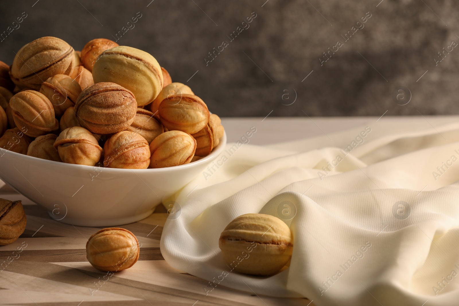 Photo of Freshly baked walnut shaped cookies on wooden board, space for text. Homemade pastry filled with caramelized condensed milk