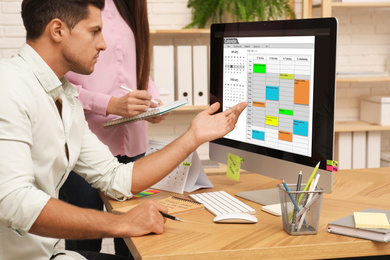 Colleagues working with calendar app on computer in office