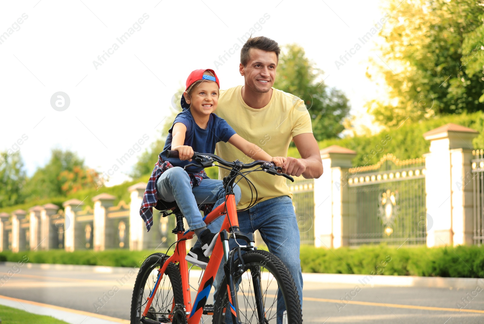 Image of Dad teaching son to ride bicycle outdoors